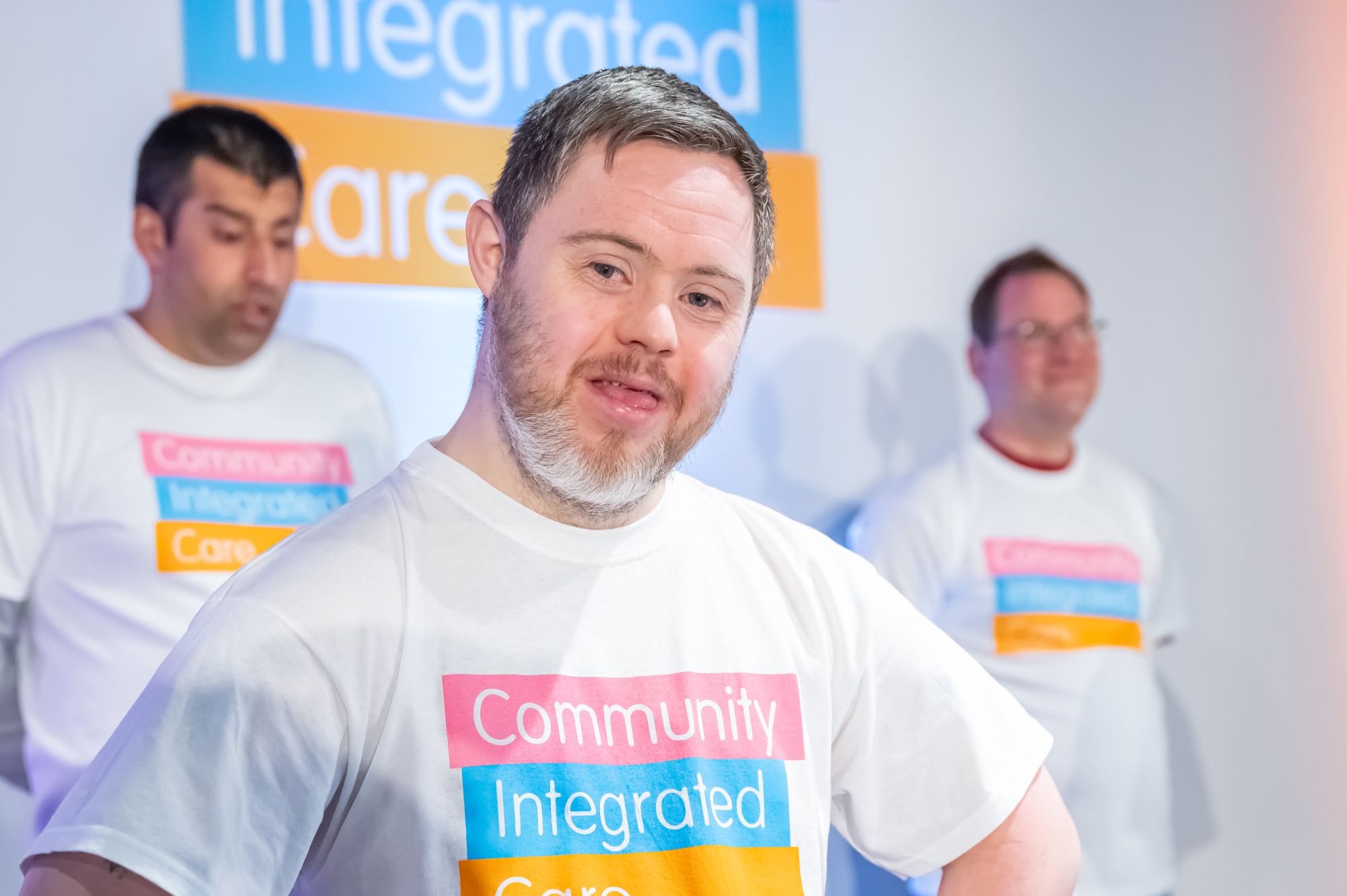 Seven individuals with a learning disability, inside a bright collaboration space with motivational wall art